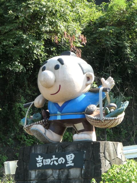 Kicchomu statue carrying vegetable baskets on a pole over his shoulder.